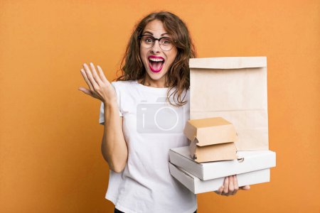 Téléchargez les photos : Hispanic pretty woman feeling happy and astonished at something unbelievable. take away fast food packages concept - en image libre de droit