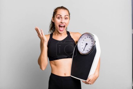 Téléchargez les photos : Hispanic pretty woman feeling happy and astonished at something unbelievable. fitness, diet and weight scale concept - en image libre de droit