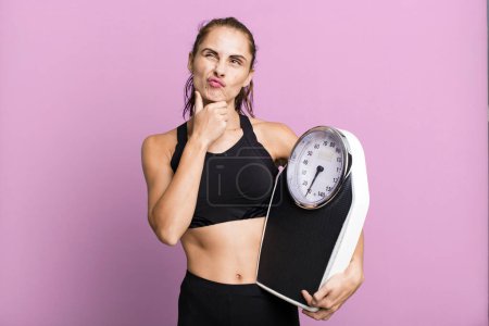 Foto de Hispanic pretty woman thinking, feeling doubtful and confused. fitness, diet and weight scale concept - Imagen libre de derechos
