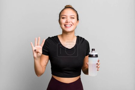 Photo for Hispanic pretty woman smiling and looking friendly, showing number four. gym and fitness concept - Royalty Free Image