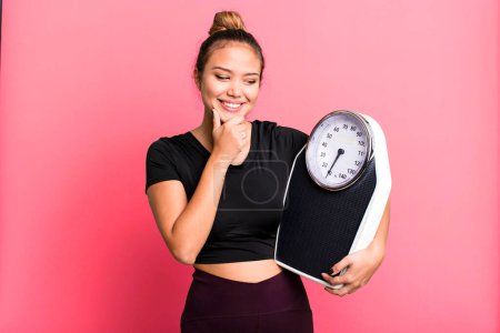 Photo for Hispanic pretty woman smiling with a happy, confident expression with hand on chin. fitness and diet concept - Royalty Free Image