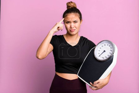 Téléchargez les photos : Hispanic pretty woman feeling confused and puzzled, showing you are insane. fitness and diet concept - en image libre de droit