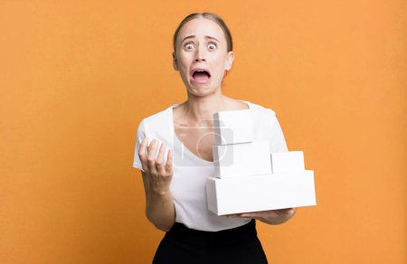 Téléchargez les photos : Caucasian pretty woman looking desperate, frustrated and stressed with white boxes packages - en image libre de droit
