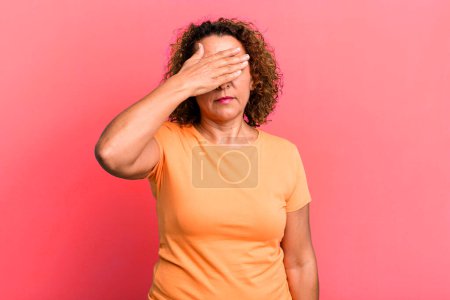 Photo for Middle age hispanic woman covering eyes with one hand feeling scared or anxious, wondering or blindly waiting for a surprise - Royalty Free Image