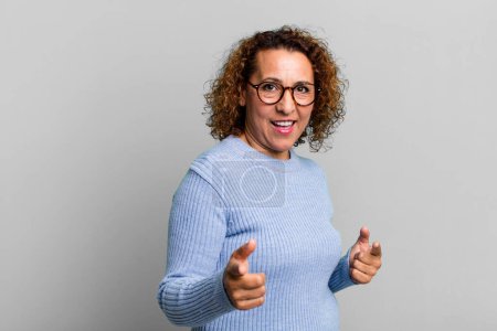 Photo for Middle age hispanic woman feeling happy, cool, satisfied, relaxed and successful, pointing at camera, choosing you - Royalty Free Image