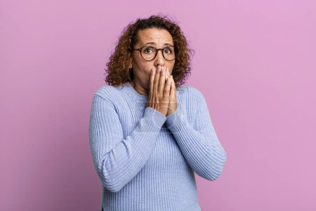 Photo for Middle age hispanic woman feeling worried, upset and scared, covering mouth with hands, looking anxious and having messed up - Royalty Free Image