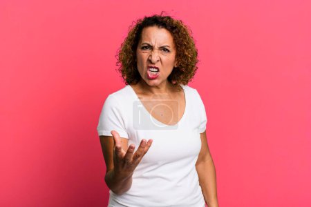 Foto de Mujer hispana de mediana edad que parece enojada, molesta y frustrada gritando wtf o lo que está mal con usted - Imagen libre de derechos