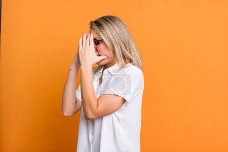 Téléchargez les photos : Blonde adult woman covering eyes with hands with a sad, frustrated look of despair, crying, side view - en image libre de droit