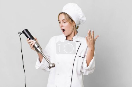 Foto de Pretty caucasian restaurant chef woman with a hand blender - Imagen libre de derechos