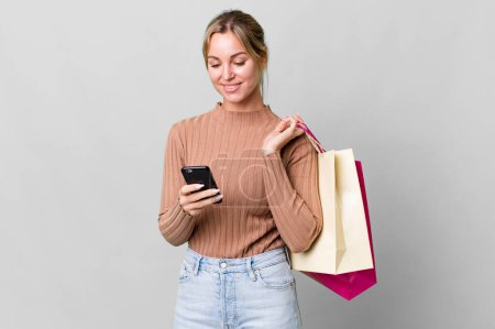 Photo for Pretty caucasian woman with shopping bags and a smartphone - Royalty Free Image