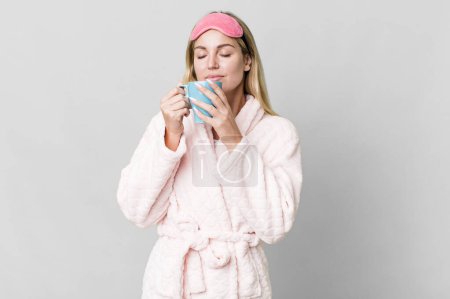 Photo for Pretty caucasian woman wearing night wear and having a coffee cup for breakfast - Royalty Free Image
