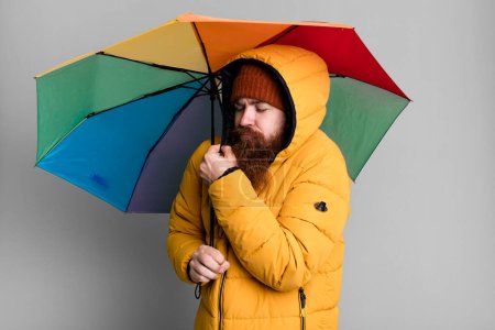Téléchargez les photos : Long beard and red hair cool man with umbrella, hat and a coat. clod and winter concept - en image libre de droit