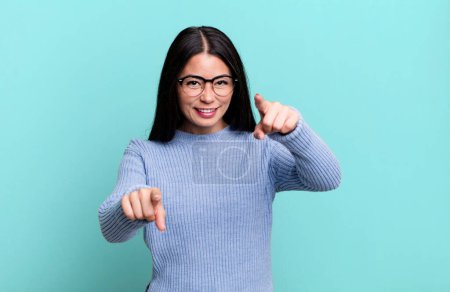 Photo for Pretty latin woman feeling happy and confident, pointing to camera with both hands and laughing, choosing you - Royalty Free Image