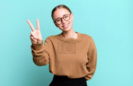 Photo for Smiling and looking happy, carefree and positive, gesturing victory or peace with one hand - Royalty Free Image