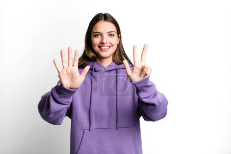 Photo for Pretty young adult woman smiling and looking friendly, showing number eight or eighth with hand forward, counting down - Royalty Free Image