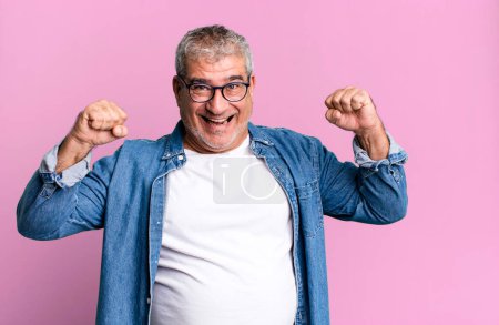 Téléchargez les photos : Homme âgé d'âge moyen se sentant heureux, positif et réussi, célébrer la victoire, réalisations ou bonne chance - en image libre de droit