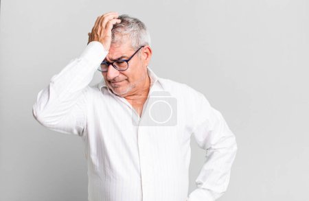 Téléchargez les photos : Middle age senior man raising palm to forehead thinking oops, after making a stupid mistake or remembering, feeling dumb - en image libre de droit