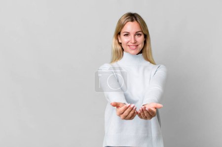 Téléchargez les photos : Caucasian blonde woman smiling happily with friendly and  offering and showing a concept. copy space concept - en image libre de droit
