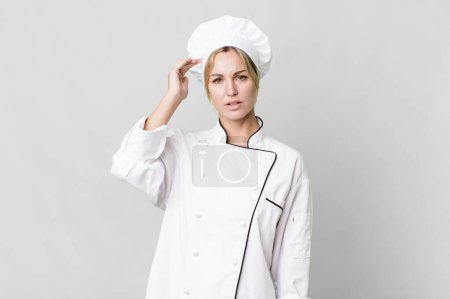 Photo for Caucasian blonde woman feeling confused and puzzled, showing you are insane. chef concept - Royalty Free Image