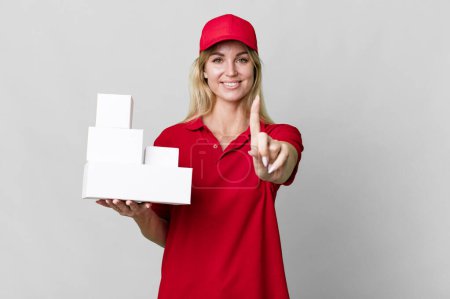 Téléchargez les photos : Caucasian blonde woman smiling proudly and confidently making number one. delivery boxes - en image libre de droit