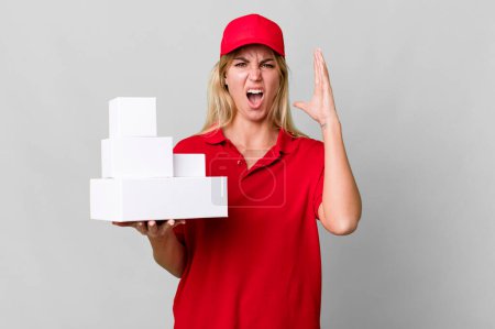 Téléchargez les photos : Caucasian blonde woman screaming with hands up in the air. delivery boxes - en image libre de droit
