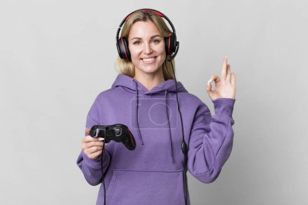 Foto de Caucasian blonde woman feeling happy, showing approval with okay gesture. gamer concept - Imagen libre de derechos