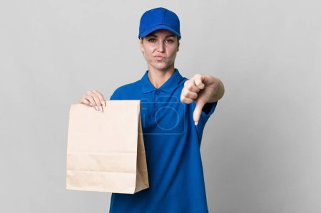 Photo for Caucasian blonde woman feeling cross,showing thumbs down. paper bag delivery concept - Royalty Free Image
