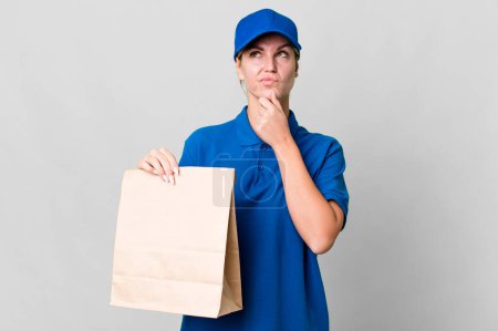 Téléchargez les photos : Caucasian blonde woman thinking, feeling doubtful and confused. paper bag delivery concept - en image libre de droit