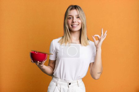 Téléchargez les photos : Young pretty woman feeling happy, showing approval with okay gesture. japanese ramen noodles concept - en image libre de droit
