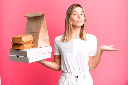 Photo for Young pretty woman feeling puzzled and confused and doubting. delivery and take away food concept - Royalty Free Image