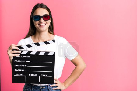 Photo for Young pretty woman smiling happily with a hand on hip and confident. cinema film or movie concept - Royalty Free Image