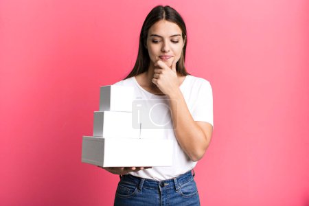Photo for Young pretty woman smiling with a happy, confident expression with hand on chin. blank white boxes - Royalty Free Image