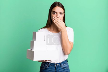 Photo for Young pretty woman covering mouth with hands with a shocked. blank white boxes - Royalty Free Image