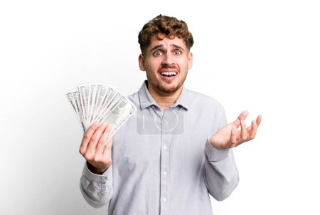 Foto de Young adult caucasian man looking desperate, frustrated and stressed. dollar bank notes concept - Imagen libre de derechos