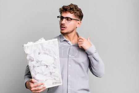 Foto de Young adult caucasian man feeling stressed, anxious, tired and frustrated with a paper balls trash concept - Imagen libre de derechos