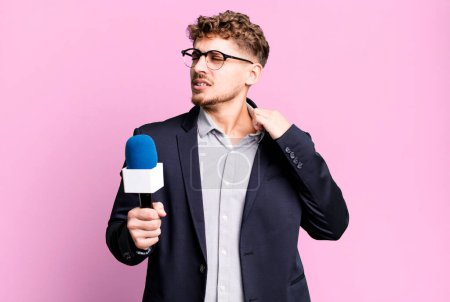 Téléchargez les photos : Young adult caucasian man feeling stressed, anxious, tired and frustrated. journalist or presenter with a microphone - en image libre de droit