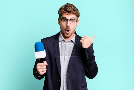 Photo for Young adult caucasian man looking astonished in disbelief. journalist or presenter with a microphone - Royalty Free Image