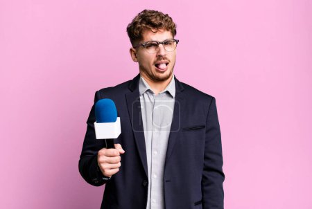 Téléchargez les photos : Young adult caucasian man feeling disgusted and irritated and tongue out. journalist or presenter with a microphone - en image libre de droit