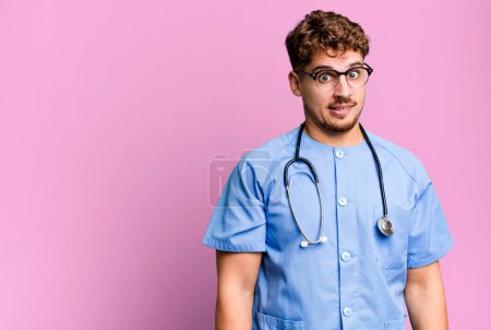 Téléchargez les photos : Young adult caucasian man looking puzzled and confused. nurse concept - en image libre de droit
