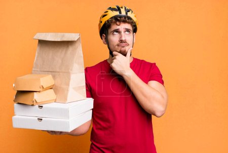 Photo for Young adult caucasian man thinking, feeling doubtful and confused.  take away fast food deliveryman concept - Royalty Free Image
