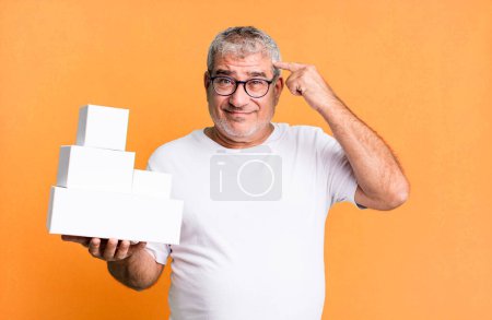 Foto de Hombre mayor de mediana edad sintiéndose confundido y perplejo, mostrando que estás loco. cajas en blanco de diferentes paquetes - Imagen libre de derechos
