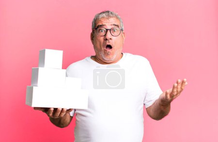 Photo for Middle age senior man amazed, shocked and astonished with an unbelievable surprise. different packages blank boxes - Royalty Free Image