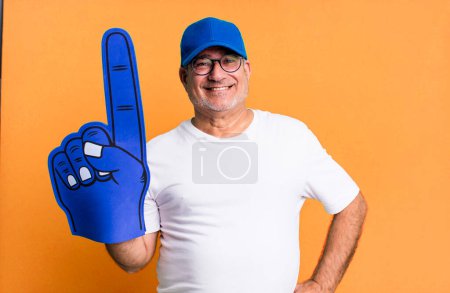 Téléchargez les photos : Senior d'âge moyen sourire heureux avec une main sur la hanche et confiant. numéro un concept de ventilateur - en image libre de droit
