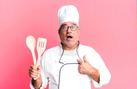 Photo for Middle age senior man looking shocked and surprised with mouth wide open, pointing to self. restaurant chef with a tool concept - Royalty Free Image