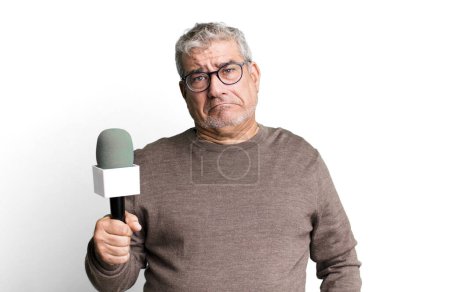 Foto de Hombre mayor de mediana edad sintiéndose triste y quejumbroso con una mirada infeliz y llorando. periodista o presentador de televisión con un micro - Imagen libre de derechos