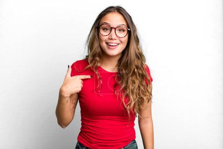 Photo for Young pretty woman looking happy, proud and surprised, cheerfully pointing to self, feeling confident and lofty - Royalty Free Image