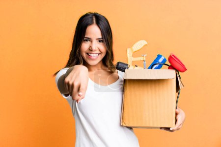 Photo for Hispanic pretty woman pointing at camera choosing you. housekeeper with a toolbox concept - Royalty Free Image