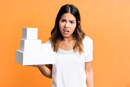 Foto de Hispanic pretty woman feeling puzzled and confused with blank packages boxes - Imagen libre de derechos