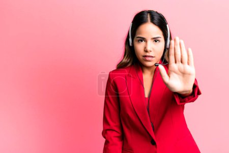 Photo for Hispanic pretty woman looking serious showing open palm making stop gesture. telemarketing concept - Royalty Free Image
