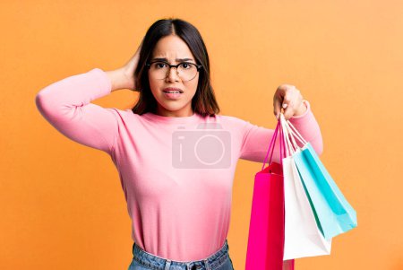 Foto de Hispanic pretty woman feeling stressed, anxious or scared, with hands on head. shopping concept - Imagen libre de derechos
